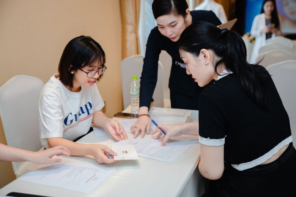 Three women collaborating in an indoor meeting, discussing documents at a table.