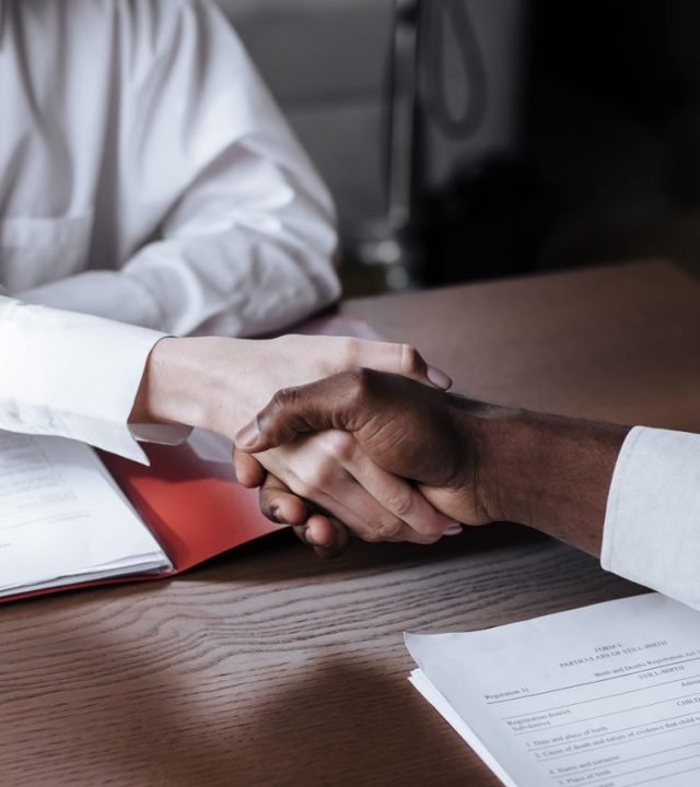 Close-up of a diverse business handshake over documents, symbolizing agreement and collaboration.